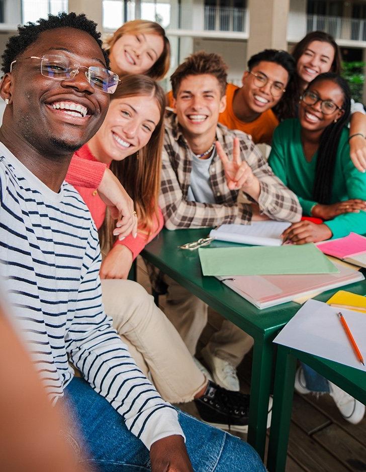 a group of diverse students take a group selfie in a classroom